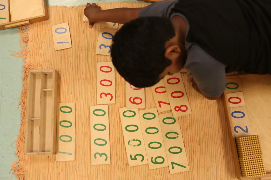 A toddler practicing fine motor skills by threading beads in a Montessori environment.