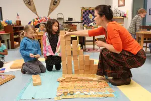 A Montessori child focused on a practical life activity, such as pouring water or arranging flowers.